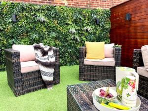 een patio met rieten stoelen en een tafel met een fruitschaal bij Lovely Central Horsham Home in Horsham