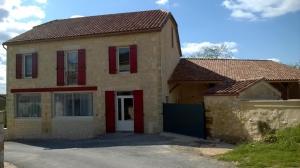 una casa con una puerta roja y un garaje en Gîte la Forge 4 étoiles, en Monségur
