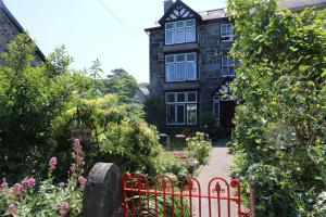 a house with a red fence in front of a garden at Dolafon in Llanbedr