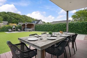 een houten tafel met stoelen en een parasol op een patio bij Villa Mastlo 2x 10 persons Ouddorp large garden, 1500 meters to the dunes and beach with 2 jacuzzi's - EXTRA COSTS APPLICABLE - not for companies in Ouddorp