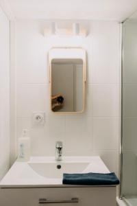 La salle de bains est pourvue d'un lavabo blanc et d'un miroir. dans l'établissement T1 Bis BOUFFAY, à Nantes