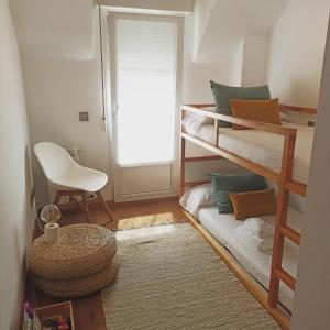 Zimmer mit 2 Etagenbetten und einem Stuhl in der Unterkunft EL ATICO in Caldas de Reis