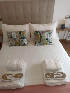 ein weißes Bett mit Handtüchern und Kissen darauf in der Unterkunft EL ATICO in Caldas de Reis