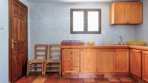 cocina con armarios de madera, fregadero y silla en Casa Madrona Periana by Ruralidays, en Periana