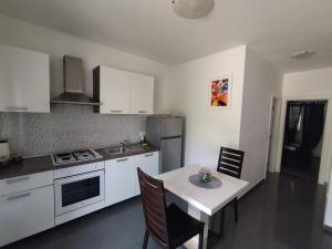 une cuisine avec des placards blancs et une table avec des chaises dans l'établissement Apartment Bila, à Šibenik