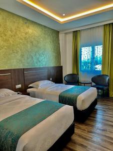a hotel room with two beds and a window at Malibest Premier in Pantai Cenang
