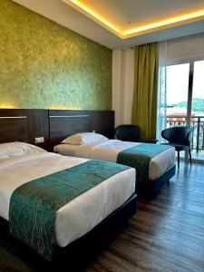 a hotel room with two beds and a balcony at Malibest Premier in Pantai Cenang