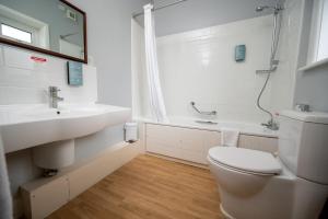 a bathroom with a toilet and a sink and a tub at Commodore Hotel by Greene King Inns in Bournemouth