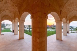 una vista de la puesta de sol a través de los arcos de un edificio en TENUTA DOROLIVO, en Otranto
