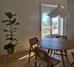 a dining room with a table and chairs and a potted plant at Casa do Poço in Setúbal