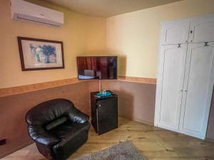 ein Wohnzimmer mit einem Ledersessel und einem TV in der Unterkunft Mátyás Vendégház Siófok in Siófok