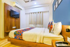 a bedroom with a bed and a desk and a television at FabHotel Hello Homz in Indore