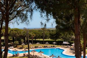 Blick auf einen Pool mit Sonnenschirmen und Stühlen in der Unterkunft Precise Resort El Rompido-The Hotel in El Rompido