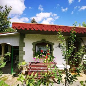 une petite maison avec un toit rouge et un banc dans l'établissement Perníková chalúpka, à Bojnice