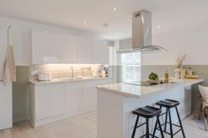 a white kitchen with white cabinets and bar stools at Southwark Serviced Apartments I Your Apartment in London