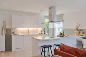 kuchnia z białymi szafkami i bar z stołkami w obiekcie Southwark Serviced Apartments I Your Apartment w Londynie
