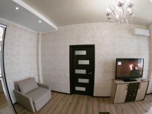 uma sala de estar com uma televisão, uma cadeira e um lustre em Апартаменты на Марсельской, Кадорр, 4я Жемчужина em Odessa