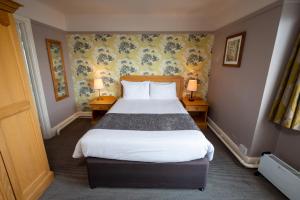 una camera d'albergo con un letto con due lampade su due tavoli di Commodore Hotel by Greene King Inns a Bournemouth