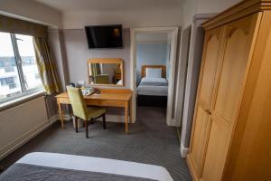 Habitación de hotel con escritorio y dormitorio en Commodore Hotel by Greene King Inns, en Bournemouth