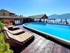 a swimming pool with lounge chairs on a wooden deck at Mustaciosul Dunarii in Eşelniţa