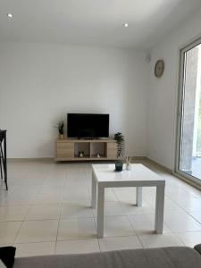 uma sala de estar branca com uma televisão e uma mesa em Appartement en résidence em La Ciotat
