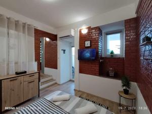 ein Wohnzimmer mit einer Ziegelwand und einem TV in der Unterkunft Apartment Tami with Swimming pool in Lovran