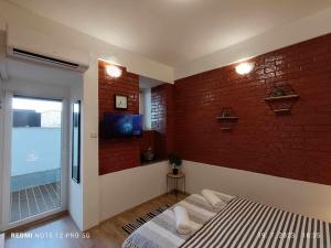 een slaapkamer met een bakstenen muur, een bed en een televisie bij Apartment Tami with Swimming pool in Lovran