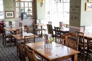 a dining room with wooden tables and chairs at Commodore Hotel by Greene King Inns in Bournemouth