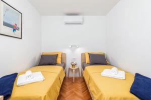 - 2 lits dans une petite chambre avec des draps jaunes dans l'établissement Sunny Aura - travel & work - with parking, à Pula