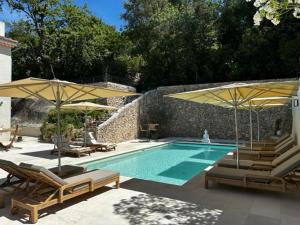 a swimming pool with umbrellas and lounge chairs and a swimming pool at Le Repos du Keyrié in Saint-Marc-Jaumegarde