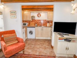 Il comprend une cuisine et un salon avec une télévision et une chaise. dans l'établissement The Little White Cottage, à Llanferres 9 autres photos