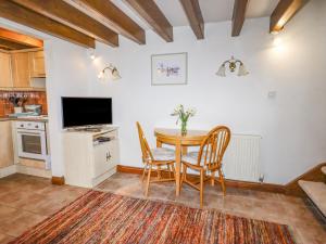 a kitchen with a table and chairs and a tv at The Little White Cottage in Llanferres