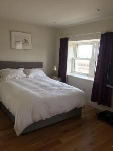 sypialnia z dużym białym łóżkiem i oknem w obiekcie 2 Quay Road, Killala. Stunning Sea Front Cottage w mieście Killala