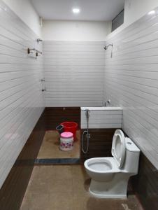 a bathroom with a toilet and a red bucket at Sambhrama Residency in Shimoga