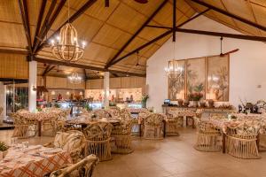 a dining room with tables and chairs and chandeliers at Hemingways Watamu in Watamu