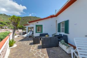 a patio with chairs and a house with a mountain in the background at Villa Oda - Bilocale sul mare in Capoliveri