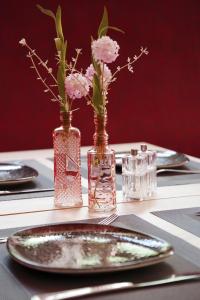 einen Tisch mit Platten und Vasen mit Blumen in der Unterkunft Hotel am Waldkasino in Erfurt