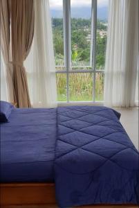 un letto blu in una stanza con una grande finestra di Homstay harian pak.anwar a Bogor