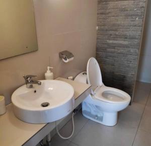 La salle de bains est pourvue d'un lavabo blanc et de toilettes. dans l'établissement Homstay harian pak.anwar, à Bogor
