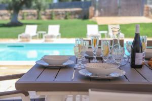 een houten tafel met wijnglazen en wijnflessen bij TD Villa Patrizia Pool & Alfresco Kitchen in Monopoli
