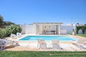 een zwembad met stoelen en een tafel en een huis bij TD Villa Patrizia Pool & Alfresco Kitchen in Monopoli