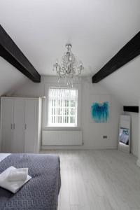 a large white room with a bed and a chandelier at Elegant 1BR Apartment, Sleeps up to 4 in Childwall