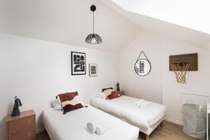 - 2 lits dans une chambre aux murs blancs dans l'établissement Le Saint Martin Bis - Bel appartement moderne et confortable, à Rennes