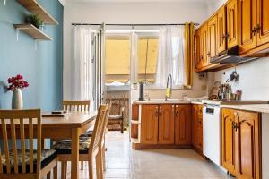 cocina con armarios de madera, mesa y comedor en Nice central family apartment en Gastoúni