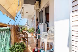 a porch with white chairs and an umbrella at Nice central family apartment in Gastoúni