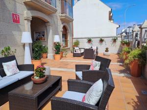 un patio con sedie, tavoli e piante di vimini di Apartamentos Playa Compostela a Vilagarcia de Arousa