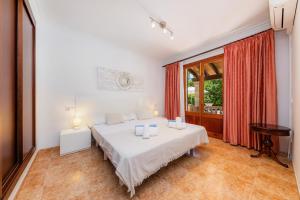 a white bedroom with a bed and a window at Pomeres Nou in Sa Coma +20 photos