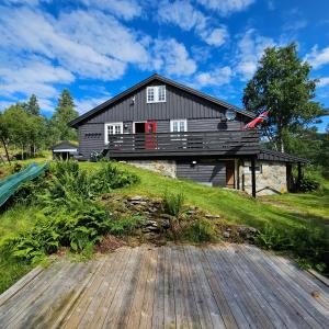 a house on a hill with a wooden deck at Bjørnebu- Ski in-ski out in Kvam
