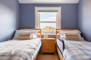 Duas camas num quarto azul com uma janela em Nina's Cottage - Southwold em Southwold