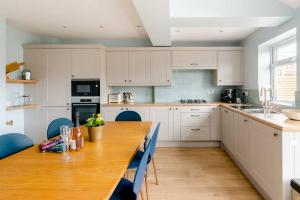 uma cozinha com uma mesa de madeira e cadeiras azuis em Nina's Cottage - Southwold em Southwold